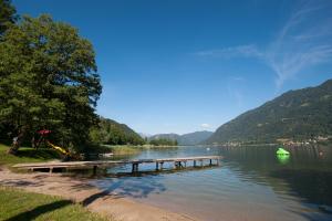 a dock on a lake with mountains in the background at Seecamping Berghof - Mobilheime in Landskron
