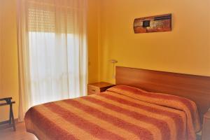 a yellow bedroom with a bed and a window at Piccolo Hotel in Rosignano Solvay