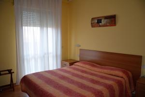 a bedroom with a bed with a striped blanket and a window at Piccolo Hotel in Rosignano Solvay