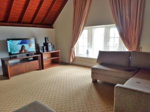 a living room with a couch and a flat screen tv at Cheltenham Cottage - Little England Cottages in Nuwara Eliya