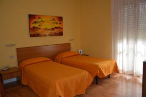 two beds in a room with orange sheets at Piccolo Hotel in Rosignano Solvay