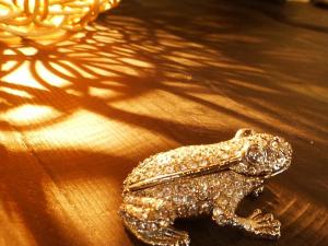a small gold frog sitting on a wooden table at Taketomijima Akaneya in Taketomi