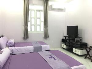 a bedroom with two beds and a flat screen tv at HT Hotel Apartment in Ho Chi Minh City