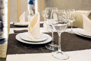 een tafel met wijnglazen en borden en servetten bij Hotel Olimp in Orenburg