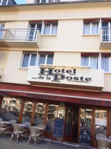 a hotel with tables and chairs in front of a building at Hôtel de la poste in Saint-Valery-en-Caux