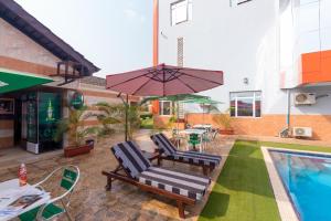 a patio with two chairs and an umbrella next to a pool at Grand Pela Hotel & Suites in Abuja