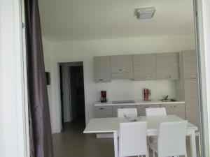 una cucina bianca con tavolo e sedie bianchi di Appartment Sunset a Lido di Jesolo