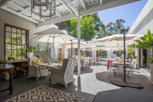 un patio con tavoli, sedie e ombrelloni di Lairds Lodge Country Estate a Plettenberg Bay