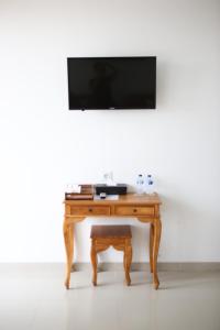 a wooden table with a television on a white wall at Grandpa Guest House in Canggu