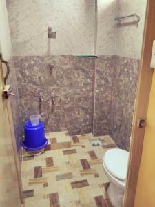 a bathroom with a toilet and a shower with a blue bucket at Vasanth Villa in Kanchipuram
