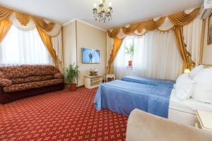 Habitación de hotel con 2 camas y sofá en Grand Hotel Uyut, en Krasnodar
