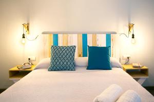 una camera da letto con un grande letto bianco con cuscini blu di HI Suite Málaga Centro a Málaga