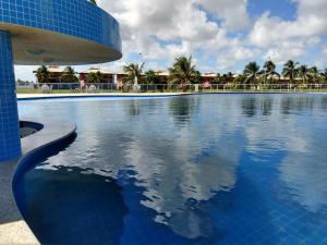 a large swimming pool with a blue building and palm trees at Condomínio Villa das Aguas com wi-fi in Praia do Saco