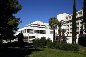 a white building with palm trees in front of it at Hotel Zagreb in Split