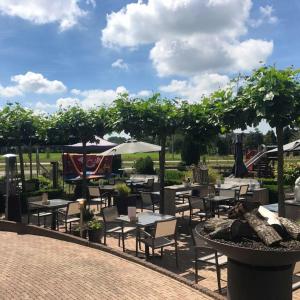 eine Terrasse mit Tischen, Stühlen und einer Feuerstelle in der Unterkunft Hotel Restaurant Het Roode Hert in Dalfsen