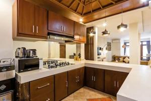 a kitchen with wooden cabinets and a stove top oven at Villa Tiah in Kuta