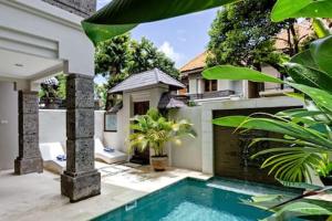a house with a swimming pool in front of a house at Villa Tiah in Kuta