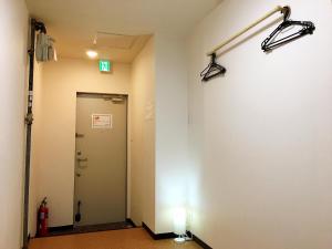 a hallway with a door and lights on the wall at Osaka Tengachaya Guesthouse SAYURI II in Osaka