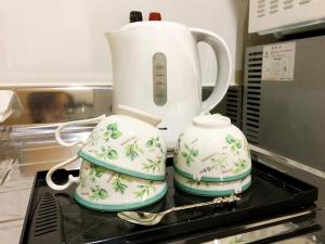 a tea pot and two cups sitting on a stove at Osaka Tengachaya Guesthouse SAYURI II in Osaka