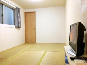 an empty room with a television and a door at Osaka Tengachaya Guesthouse SAYURI II in Osaka