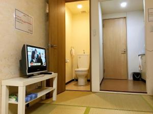 a bathroom with a toilet and a television on a table at Osaka Tengachaya Guesthouse SAYURI II in Osaka