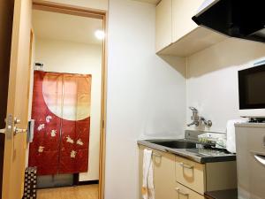 a small kitchen with a sink and a counter at Osaka Tengachaya Guesthouse SAYURI II in Osaka