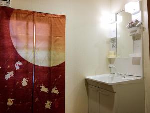a bathroom with a sink and a shower curtain at Osaka Tengachaya Guesthouse SAYURI II in Osaka