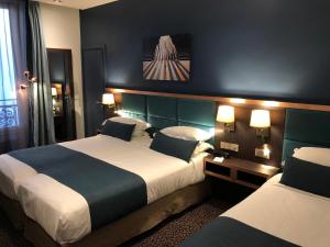 a hotel room with two beds and two lamps at Best Western Empire Elysees in Paris