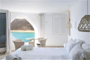 a bedroom with a bed and a view of a beach at Panormos Village Hotel in Mykonos