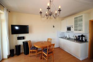 a kitchen with a table and chairs and a chandelier at Fuerstenhof Appartement 401 in Sassnitz