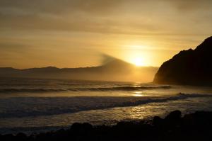 a sunset on the beach with a mountain in the background at Apartamentos Los Telares in Hermigua