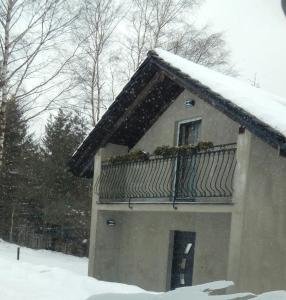 ヴィスワにあるNowy domek Jarzębiankaの雪の中のバルコニー付きの家