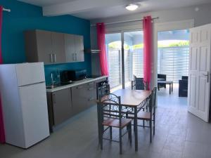 a kitchen with a table and chairs and a refrigerator at Le Domaine Turquoise in Le Moule