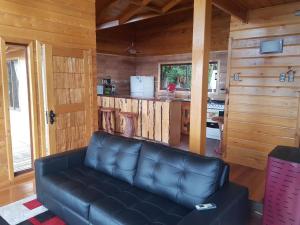 a leather couch in a living room with a kitchen at Cabana Chiloe in Queilén