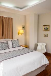 um quarto com uma cama e uma cadeira em La Coupole Hotel em Quito