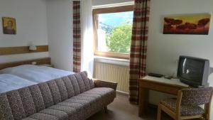1 dormitorio con 1 cama, TV y silla en Garni Mühlanger en Tirolo