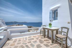 uma varanda com uma mesa e um lavatório e o oceano em Golden Sunset Villas em Agios Ioannis
