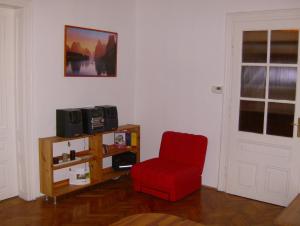 een woonkamer met een rode stoel en een tv bij Csapd le Csacsi Vendégház in Pécs