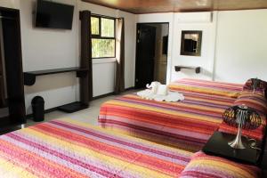 um quarto de hotel com duas camas e uma televisão em Hotel Arenal Country Inn em La Fortuna