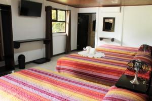 a hotel room with two beds and a tv at Hotel Arenal Country Inn in Fortuna
