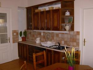 een keuken met houten kasten, een wastafel en een tafel bij Csapd le Csacsi Vendégház in Pécs