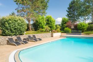 a swimming pool with lounge chairs next to a stone wall at Logis Hotel Le Sablier du Temps in Argentat