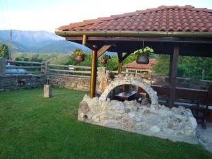 a stone fireplace in the grass under a gazebo at Guest House Tsvetina in Apriltsi