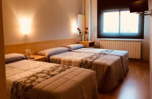 Una habitación de hotel con dos camas y una ventana. en Hotel Viñas 17, en Teruel