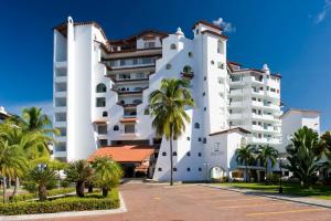 ein großes weißes Gebäude mit Palmen davor in der Unterkunft Vamar Vallarta Marina & Beach Resort in Puerto Vallarta