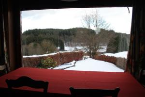 a window view of a snowy yard with a table and chairs at Le Piroy in Saint-Hubert