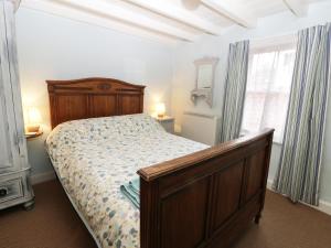 ステイスにあるWaycot Cottageのベッドルーム1室(木製フレームのベッド1台、窓付)