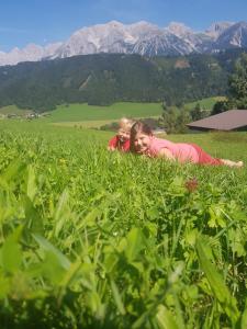 zwei Mädchen, die auf einem Feld im Gras liegen in der Unterkunft Götschlhof in Schladming