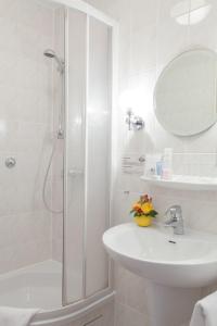 a white bathroom with a shower and a sink at Hotel Benn in Berlin