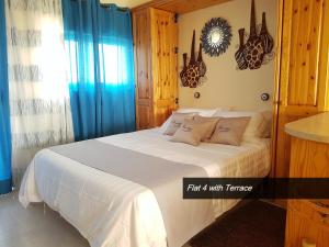1 dormitorio con cama blanca y cortinas azules en Pretty Bay Apartments, en Birżebbuġa